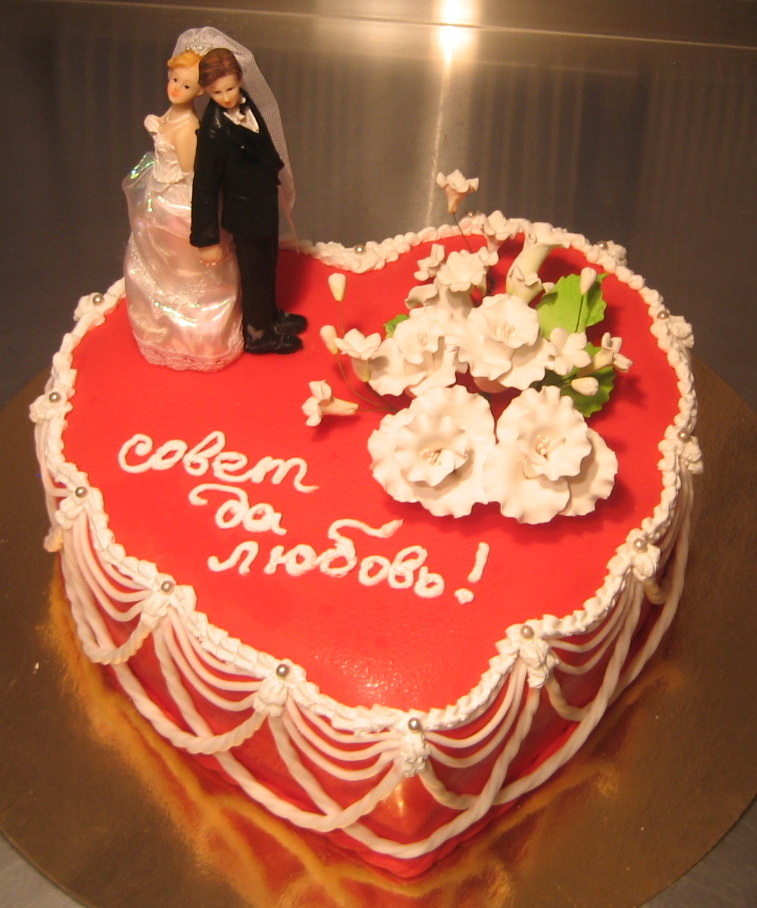 Свадебный торт в виде сердца с цветами и фигуркой жениха и невесты